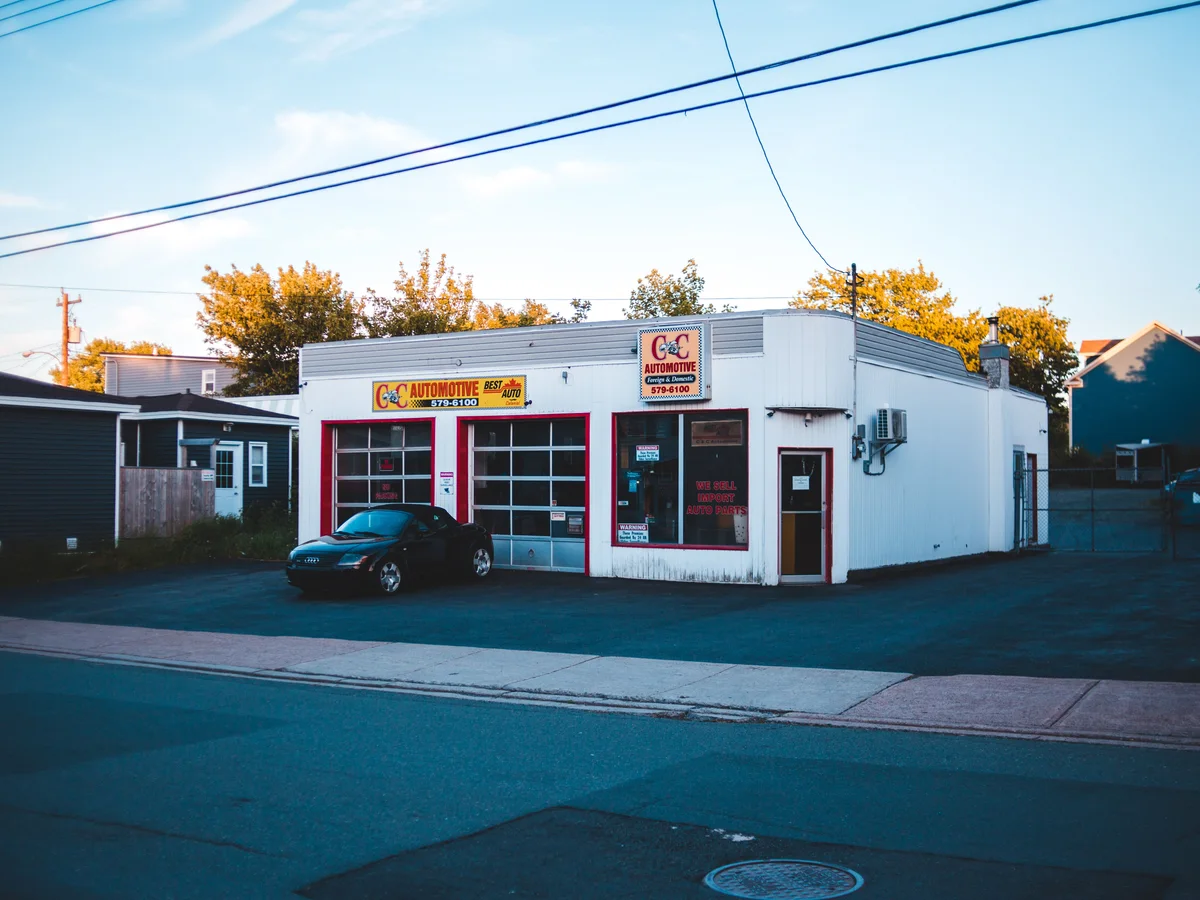 A neighborhood auto repair shop with service bays, clear signage, and a car parked outside