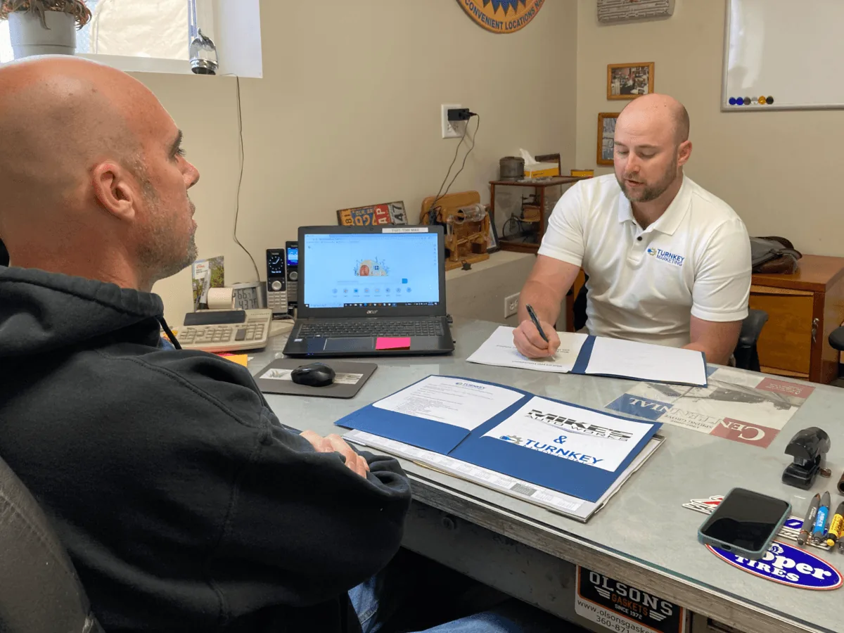 A Turnkey Marketing team member discussing a plan across an auto shop counter